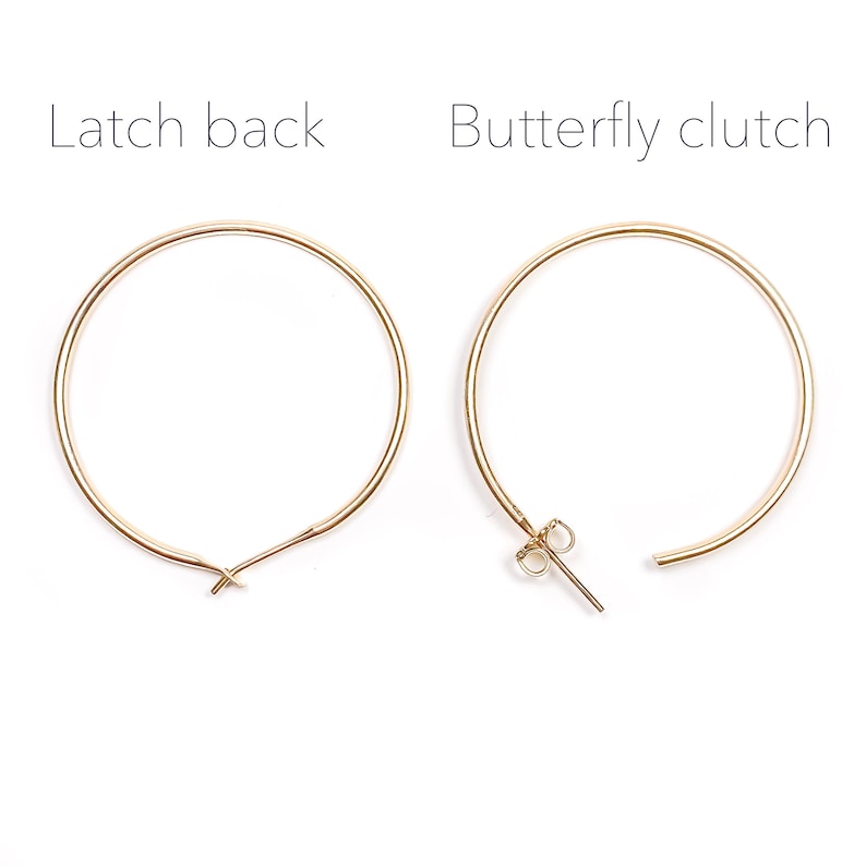 May include: A pair of gold hoop earrings with a latch back closure on the left and a butterfly clutch closure on the right.