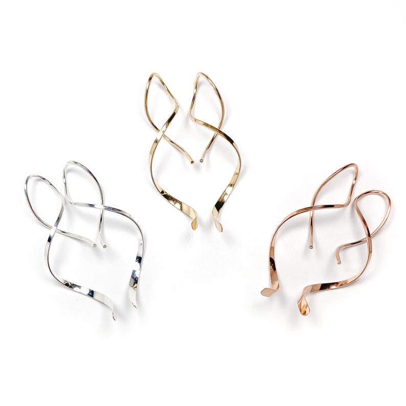May include: Three pairs of twisted wire earrings in silver, gold, and rose gold.