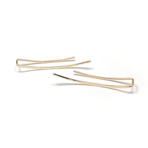 May include: A pair of gold ear cuffs with a hammered finish. The cuffs are simple and elegant, and they would make a great addition to any jewelry collection.