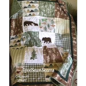 Könnte beinhalten: Eine grüne und braune Babydecke mit Waldmotiv. Die Decke zeigt gestickte Bären, Bäume und Hirsche. Die Decke ist 38 Zoll mal 46 Zoll groß und wurde von LoveSewnSeams hergestellt.