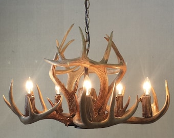 May include: A rustic chandelier made from antlers with six light bulbs. The chandelier is hanging from a chain and has a natural wood finish.
