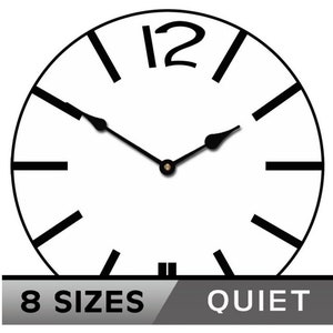 May include: A black and white clock face with black hour and minute hands. The clock face has black Roman numerals for the hours. The clock face is round and has a white background. The text "8 SIZES" and "QUIET" is visible below the clock face.