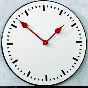 May include: A white clock face with black markings and red hands. The clock has a black rim and is set against a white tiled background.