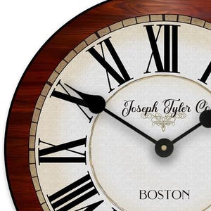 May include: A round wall clock with a dark wood grain frame. The clock face is off-white with black Roman numerals and black hands. The text "Joseph Tyler Co." and "BOSTON" are printed on the face.