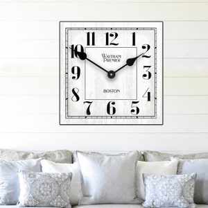 Puede incluir: Reloj cuadrado blanco con números romanos negros y agujas negras. La esfera del reloj tiene el texto "Waltham Premier Boston".