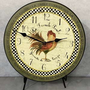 May include: A black and white checkered clock with a rooster illustration and the text "Le French Poule" and "Girouette de Beau Temps". The clock has black hands and a black stand.