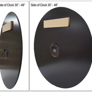 May include: Back view of a black round clock with a diameter of 30 inches. The clock has a white wooden hanging bracket and a small black clock mechanism.