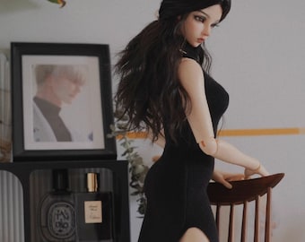 May include: A black doll with long black hair wearing a black dress with a slit up the side and black knee-high boots. The doll is kneeling on a wooden chair.