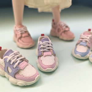 May include: Four pairs of pink and blue sneakers with white laces. The sneakers have a chunky white sole and a mesh upper.