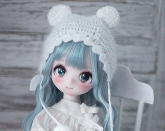 May include: A doll with blue hair and a white crocheted hat sits on a white chair. She is wearing a white dress and black and white checkered socks. She is holding a small basket filled with flowers.