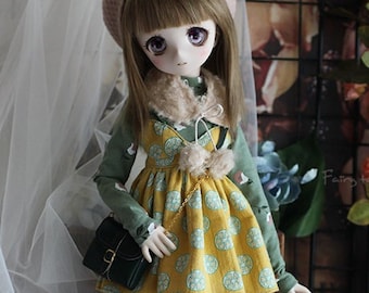 May include: A doll wearing a green and yellow dress with a pink hat and a green purse. The doll has brown hair and purple eyes. The doll is standing on a clear stand.