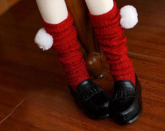 Pode incluir: Um par de meias vermelhas até ao joelho com pompons brancos no topo. As meias são usadas com sapatos pretos.