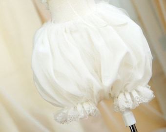 May include: White tulle babydoll with lace trim and a satin bow. The babydoll is on a white mannequin and has a gathered skirt.