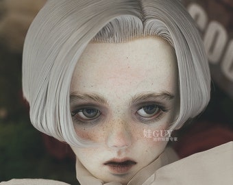 May include: A doll with a short, silver wig, wearing a white shirt with a large bow tie. The doll has a neutral expression and light brown eyes.