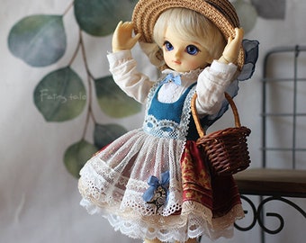 May include: A doll wearing a white blouse, a blue and white dress with lace trim, a brown straw hat, white socks, and red shoes. The doll is holding a brown wicker basket.