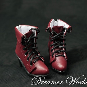 Puede incluir: Un par de botines de cuero burdeos con cordones negros y un peque&ntilde;o tac&oacute;n. Las botas tienen una cremallera en el lateral y est&aacute;n hechas de cuero texturizado.