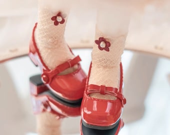 May include: A pair of red patent leather shoes with a bow detail and a small flower embellishment on each shoe.