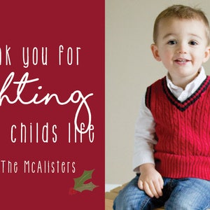 May include: A red Christmas card with white text that reads "Thank you for lighting up our child's life. Love, The McAlister's". A young boy wearing a red sweater vest and blue jeans is sitting on a wooden surface.