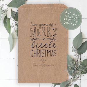 May include: A brown paper bag with a black printed design that says "have yourself a MERRY little CHRISTMAS" and "Love, The Lafrinere's". The bag has a white circle with black text that says "ADD ANY CUSTOM TEXT OR QUOTE!"