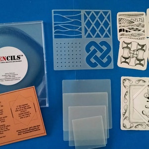 May include: A set of Zencils, a type of stencil for creating intricate designs. The set includes four clear plastic stencils, four sample tiles with completed designs, and a clear plastic disc with the Zencils logo. The text "Zencils™ Expand Your Creative Boundaries" is printed on the disc. The set also includes a small orange card with instructions.
