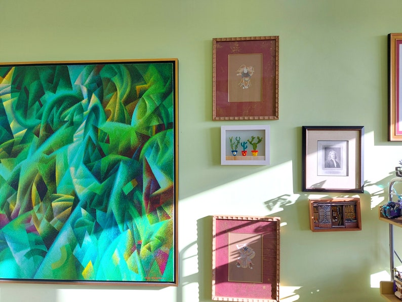K&ouml;nnte beinhalten: Eine Wandgalerie mit verschiedenen gerahmten Kunstwerken, darunter ein gro&szlig;es abstraktes Gem&auml;lde in Gr&uuml;n- und Blaut&ouml;nen, ein gerahmter Druck mit rotem Rahmen, ein kleiner gerahmter Druck mit drei Topfkakteen, ein gerahmtes Schwarzwei&szlig;foto und ein gerahmter Druck aus Holz mit geometrischem Muster.