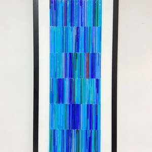 May include: A framed artwork made of blue, green, and red glass rods arranged in a vertical pattern.