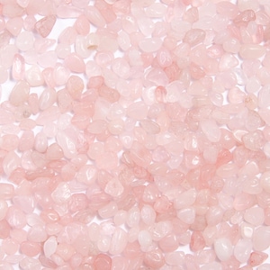 May include: A collection of small, tumbled rose quartz stones featuring a translucent, pale pink color. Each stone has a smooth, rounded surface with irregular shapes and sizes, creating a dense, uniform layer of light pink mineral fragments.