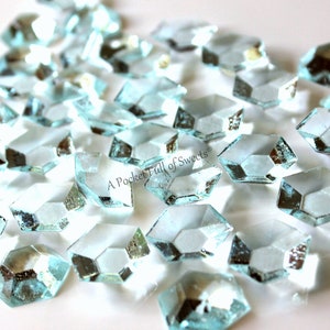 Peut inclure: Un tas de bonbons en sucre bleu clair, facet&eacute;s, en forme de diamants. Les bonbons sont sur une surface blanche. "A Pocket Full of Sweets" est &eacute;crit en noir sur les bonbons.