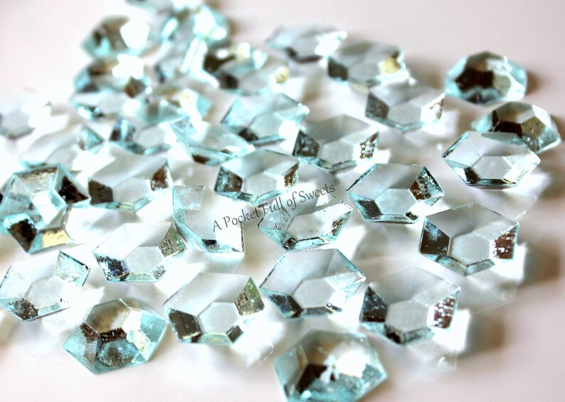 Peut inclure: Un tas de bonbons en sucre bleu clair, facet&eacute;s, en forme de diamants. Les bonbons sont sur une surface blanche. "A Pocket Full of Sweets" est &eacute;crit en noir sur les bonbons.