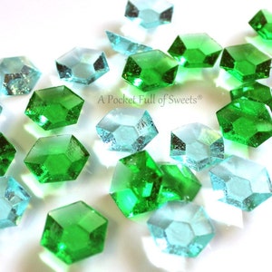May include: A collection of green and blue hexagonal candy gems. The candy is shaped like gemstones and has a shiny, translucent finish. The text "A Pocket Full of Sweets®" is visible in the image.