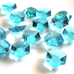 Peut inclure: Une dispersion de bonbons bleus turquoise en forme d'octogones. Les bonbons sont dispos&eacute;s sur une surface blanche.
