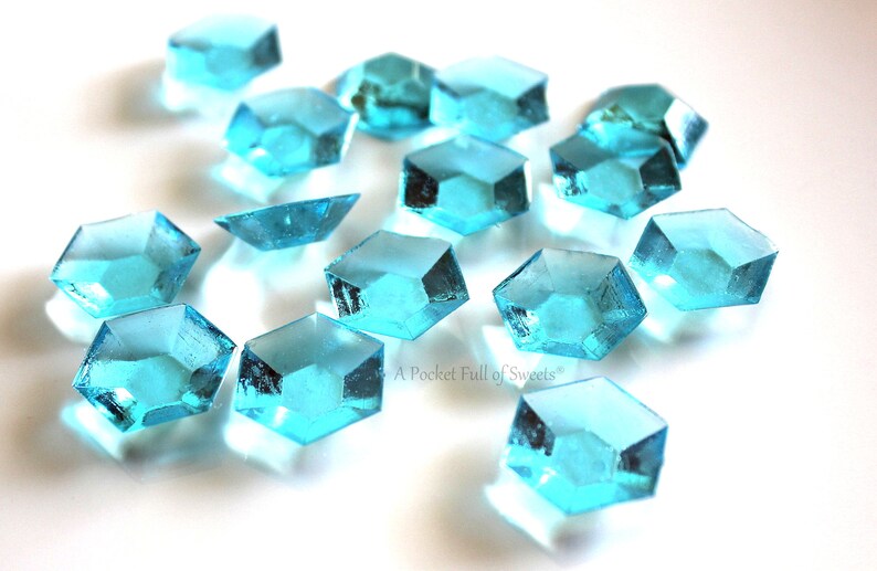 Peut inclure: Une dispersion de bonbons bleus turquoise en forme d'octogones. Les bonbons sont dispos&eacute;s sur une surface blanche.