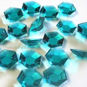 Peut inclure: Des bonbons bleus turquoise en forme de diamants multifacettes &eacute;parpill&eacute;s sur une surface blanche.  A Pocket Full of Sweets.
