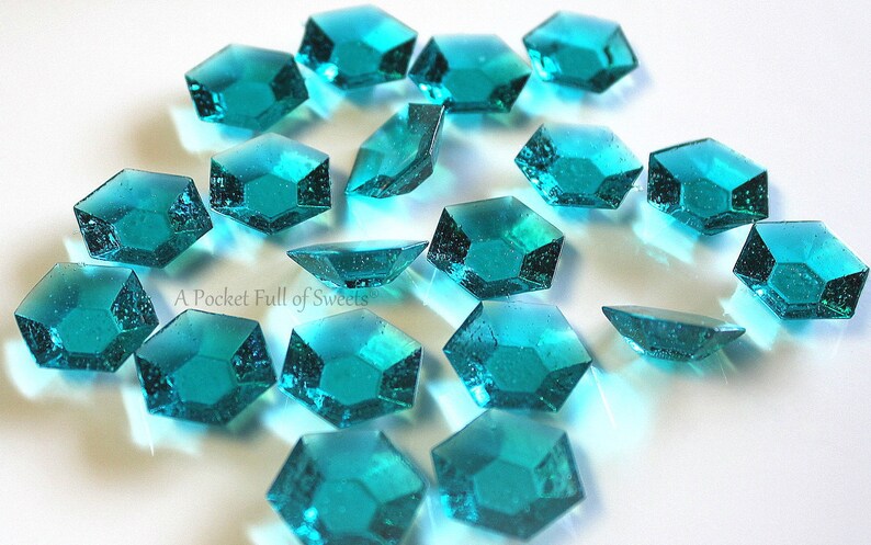 Peut inclure: Des bonbons bleus turquoise en forme de diamants multifacettes &eacute;parpill&eacute;s sur une surface blanche.  A Pocket Full of Sweets.