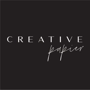 May include: Black background with the words "CREATIVE" in a serif font and "papier" in a cursive script, both in white. The design is simple and elegant, suitable for branding or stationery.