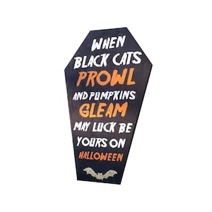 May include: Black coffin-shaped Halloween sign with white and orange text that reads "When Black Cats Prowl and Pumpkins Gleam May Luck Be Yours on Halloween." A glittery bat is at the bottom.