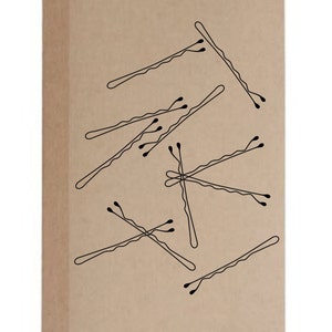 May include: A tan notebook with a collection of black bobby pins scattered across the cover. The bobby pins are drawn in a simple, minimalist style, with a wavy shape and small, rounded tips. The notebook has a plain, unadorned design.