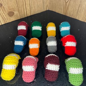 May include: A collection of 14 crocheted hats in various colors, including red, green, yellow, orange, blue, pink, and gray. Each hat has a white crocheted brim.
