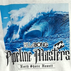 May include: White t-shirt with a blue wave graphic and the text "BILLABONG Pipeline Masters North Shore Hawaii". The design includes the Billabong logo and a stylized wave.