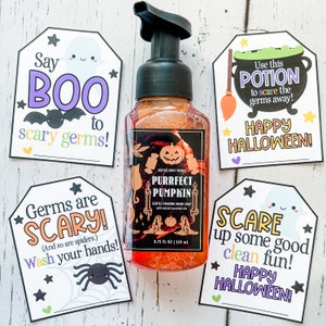May include: Four Halloween-themed gift tags with a bottle of pumpkin-scented hand soap. The tags feature ghosts, bats, spiders, and a cauldron. The text on the tags reads "Say Boo to scary germs!", "Germs are SCARY! (And so are spiders.) Wash your hands!", "Use this POTION to scare the germs away! Happy HALLOWEEN!" and "SCARE up some good clean fun! HAPPY HALLOWEEN!"