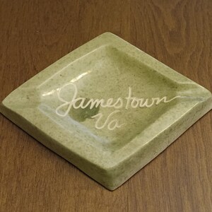 May include: A green ceramic ashtray with the words "Jamestown Va" written in white.