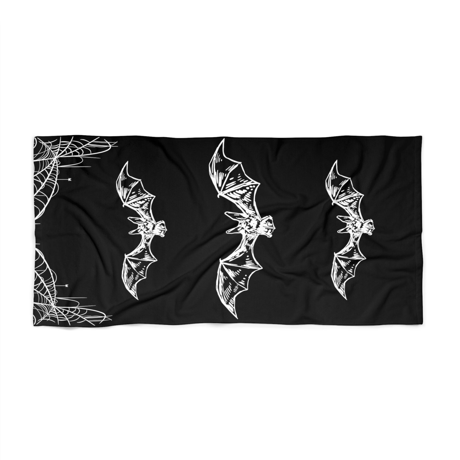 Gothic beach towel with three white bats and spiderweb corners on black background, perfect for beach goth looks.