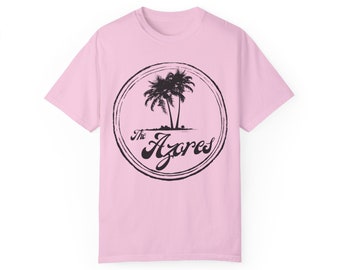 Op de afbeelding: Roze T-shirt met een zwart-witte afbeelding van palmbomen en de tekst "The Azores" in een cirkel.