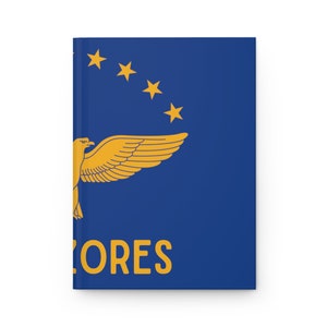 Könnte beinhalten: Ein Notizbuch mit blauem Einband, das ein goldenes Adleremblem, fünf goldene Sterne und das Wort "AZORES" in Gold zeigt.