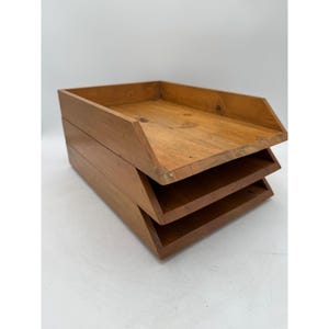 May include: A three-tiered wooden document tray with a natural light brown finish. The organiser features three stacked, open-front compartments with angled side panels, constructed from solid wood with visible grain and knots throughout.