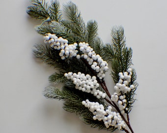 May include: A sprig of artificial greenery with white berries. The sprig is perfect for adding a touch of winter to your home decor.