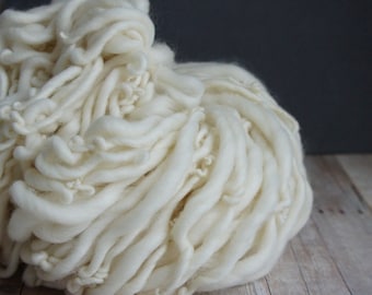 May include: A large pile of white yarn, resembling a fluffy cloud. The yarn is soft and textured, perfect for knitting or crocheting.