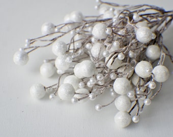 May include: White berry sprigs with small, glittery white berries. The berries are clustered together on thin, silver-colored stems.