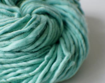 May include: A close-up of a skein of teal blue yarn. The yarn is soft and fluffy, and it is perfect for knitting or crocheting.