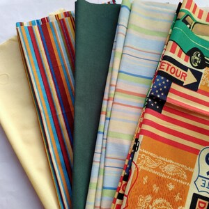 May include: A collection of fabric swatches in various colors and patterns. Includes solid yellow, vertical stripes in red, blue, and yellow, solid green, striped blue and green, and a patterned fabric with a vintage car, American flag, and Route 99 sign.